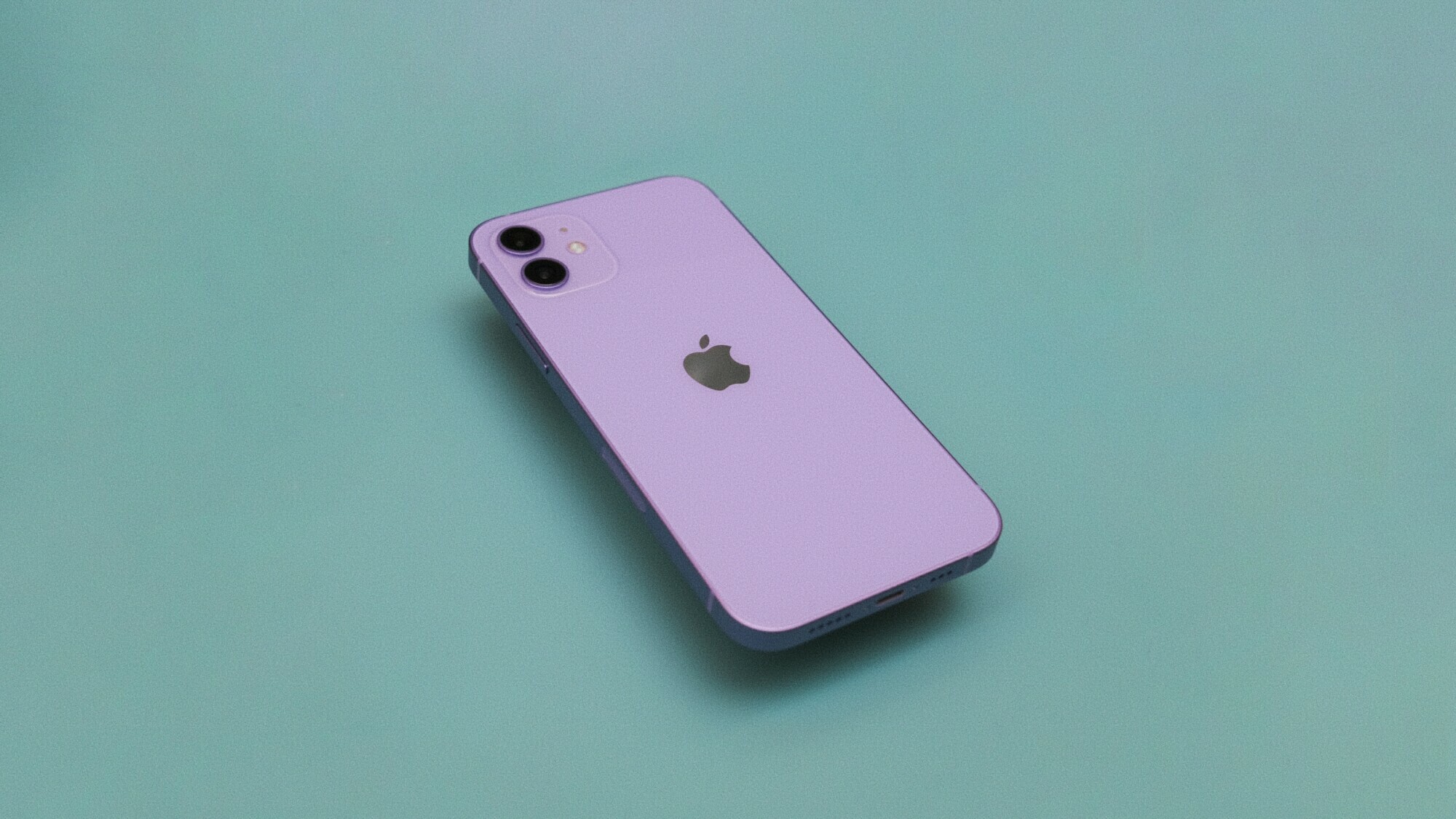 El iPhone 12 violeta claro está boca abajo sobre una superficie verde.